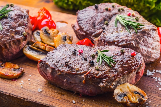 Raw beef steaks on wooden board with spices and herbs.