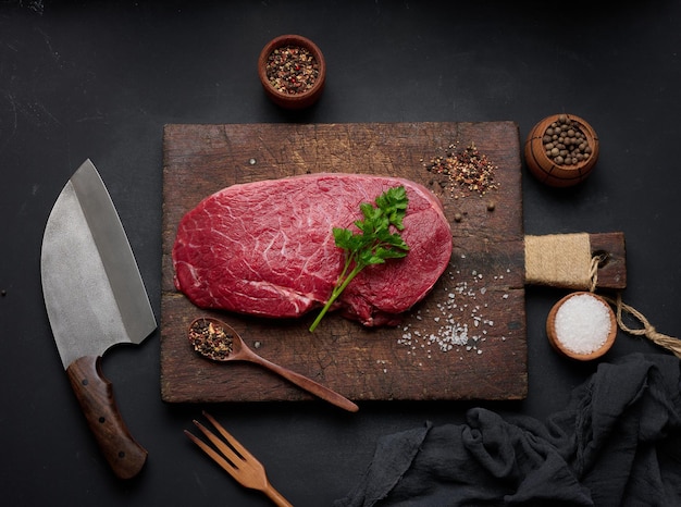 Raw beef tenderloin lies on a brown wooden board black table