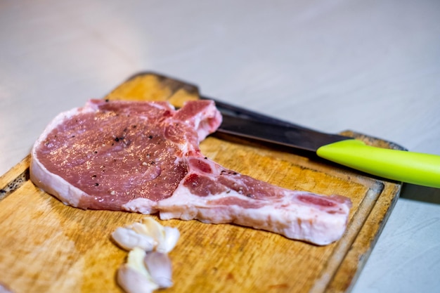 Raw beef with garlic and knife on wood chopping block