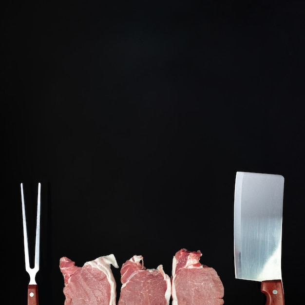 Photo raw beef with seasoning knife and meat fork on dark background fillet steak beef meat fresh meat in row with spices