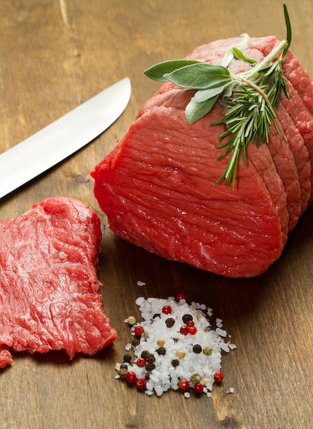 Raw beef on wooden table with rosemary ,sage and salt