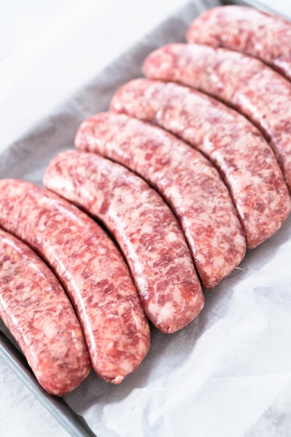 Raw beer bratwursts in the row on a small tray.