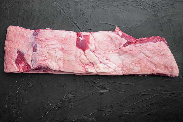 Raw Black Angus Marbled Beef Ribs set, on black stone background, top view flat lay, with copy space for text