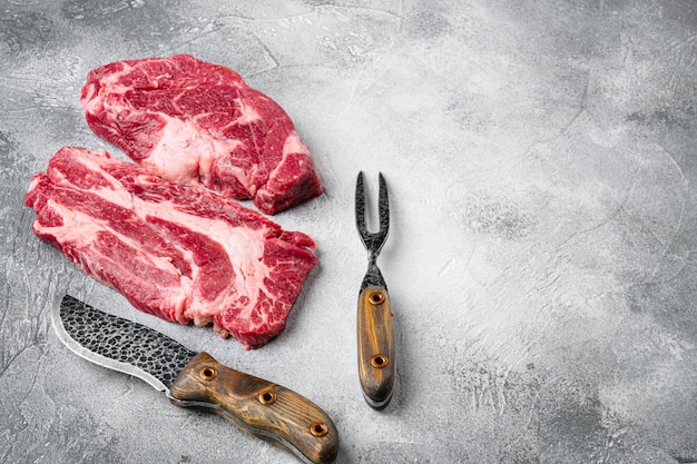 Raw Black Angus Prime meat steak set, on gray stone table background, with copy space for text