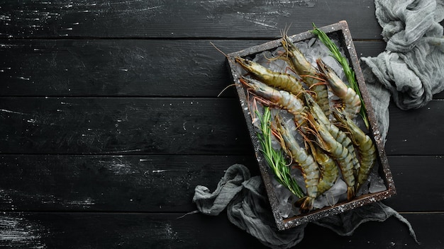 Raw black tiger prawns with lemon. Seafood. Top view. On a black background. Free copy space.
