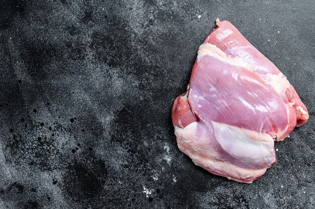 Raw boneless Turkey thigh fillet. black background. Top view. Copy space.