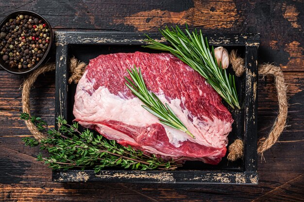 Raw brisket beef meat cut on a wooden tray with knife