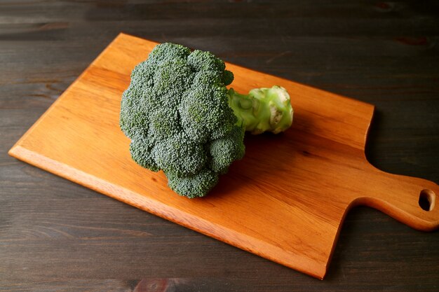 Broccoli crudi isolati su un tagliere di legno