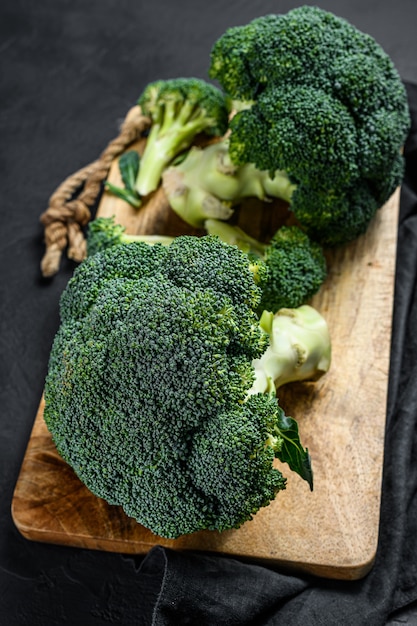 Raw broccoli in a wooden bowl. Black background. Top view