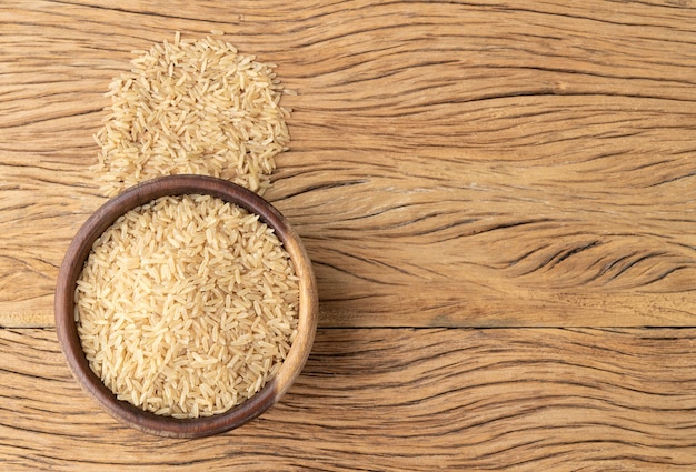 Raw brown rice in a bowl over wooden table with copy space