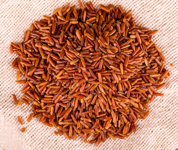 Raw brown rice l on sackcloth background.