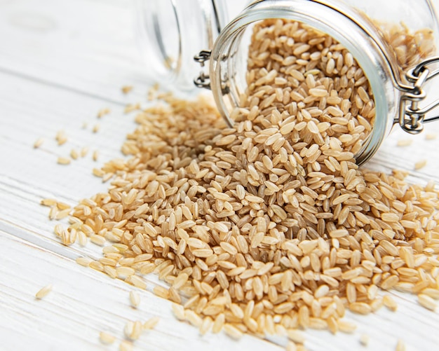 Raw brown rice on white wooden background