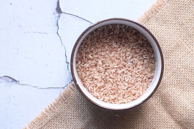 Raw brown rice on wooden background top down.