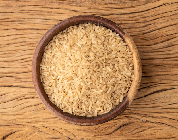 Raw brown whole rice in a bowl over wooden table