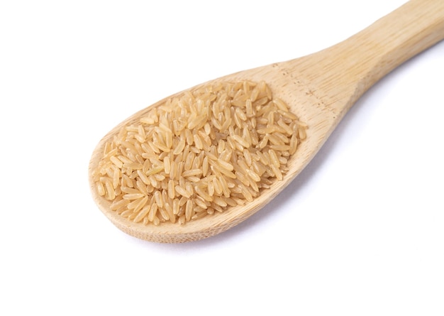 Raw brown whole rice in a spoon isolated over white background