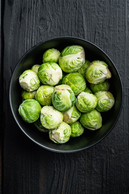 Raw brussels sprouts, on black wooden table, flat lay