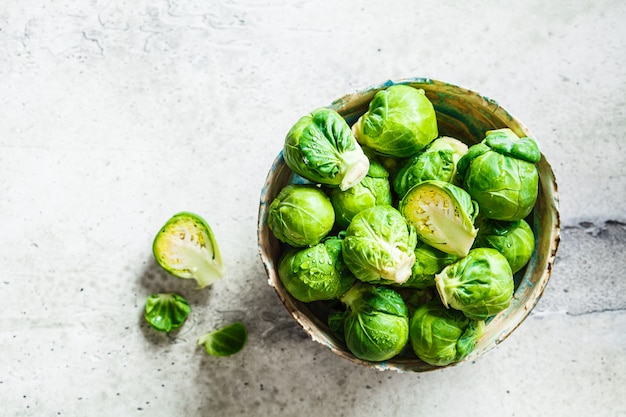 Raw brussels sprouts in bowl, gray concrete background