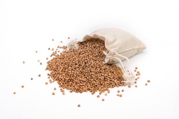 Raw buckwheat in a linen or jute bag on a white space.