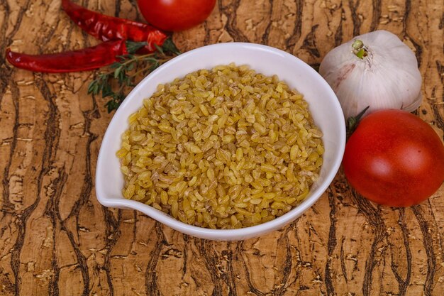 Raw bulgur in the bowl with tomatoes and garlic