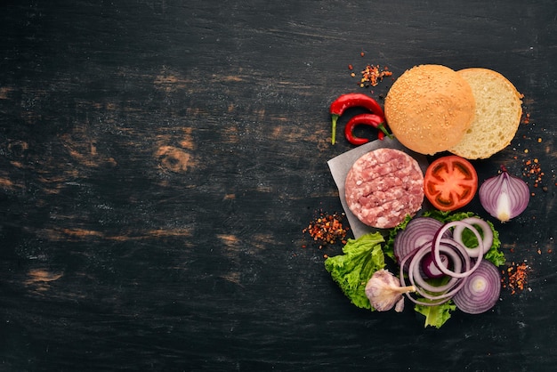 Raw burger Cooking a burger with meat On a black wooden background Top view Free copy space