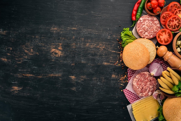 Raw burger Cooking a burger with meat. On a black wooden background. Top view. Free copy space.