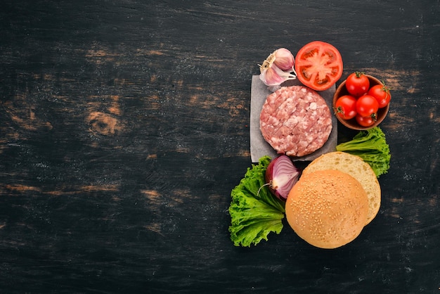 Raw burger Cooking a burger with meat On a black wooden background Top view Free copy space