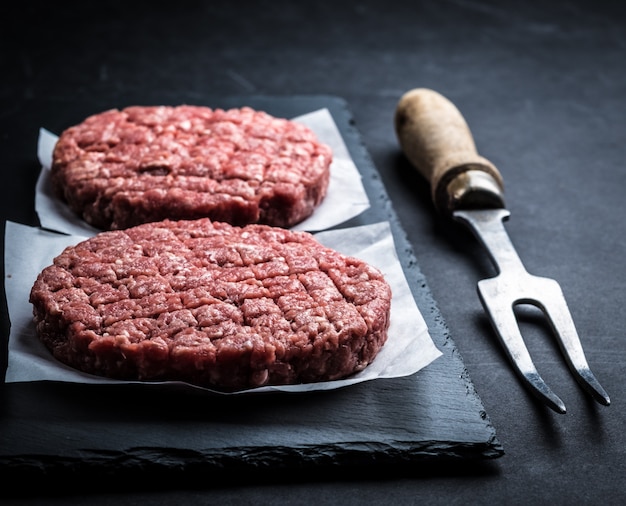 Raw burger cutlet on cooking slate