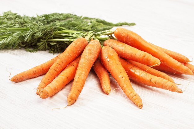 Raw carrots with leaves on a white wooden table