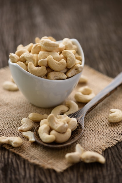 Photo raw cashew nuts in white ceramic bowl on wood table