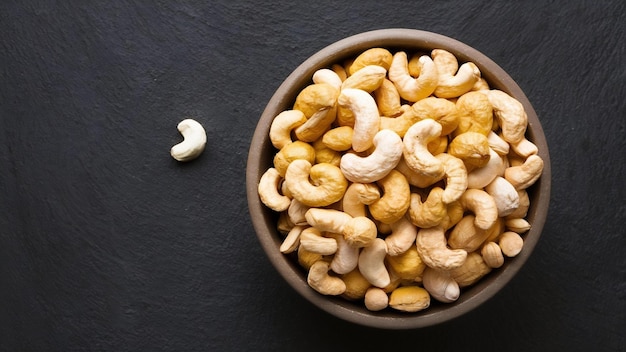 Raw cashews nuts in bowl on dark background