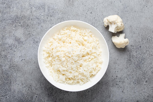 Raw cauliflower rice or couscous in a white bowl healthy low