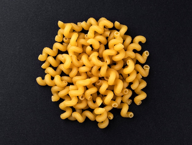 Raw cellentani pasta isolated on black background