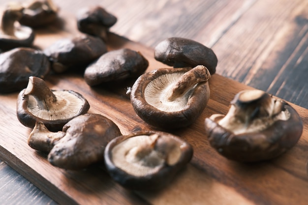 Raw champignon mushroom on a chopping board on table