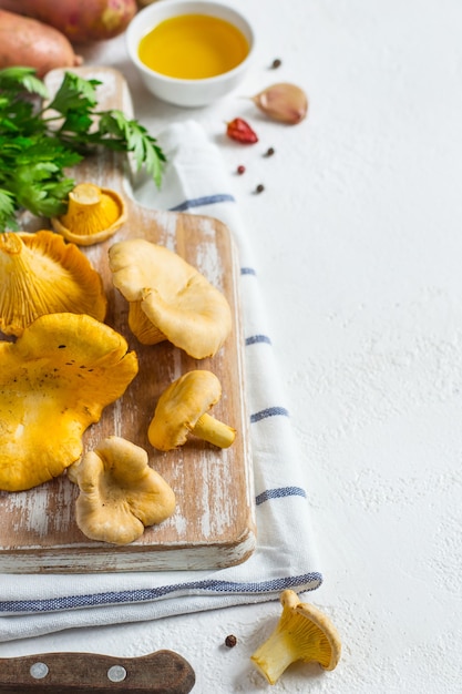 Raw chanterelle mushrooms on a cutting board closeup on white background