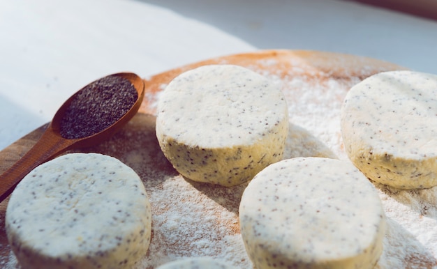 Raw cheese cakes with poppy seeds on a wooden surface