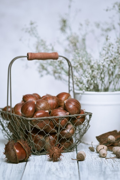 Raw chestnuts on a wooden in an iron basket.