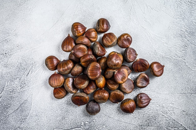 Raw chestnuts on a wooden table. White background. Top view.