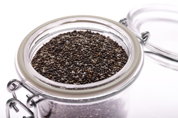 Raw Chia seeds in clear glass airtight jar on white background