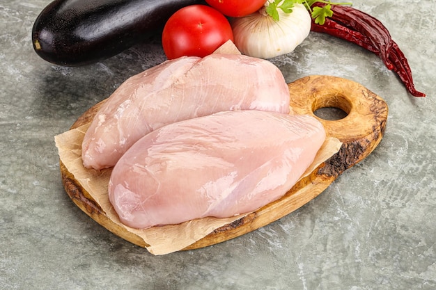 Raw chicken breast over board for cooking