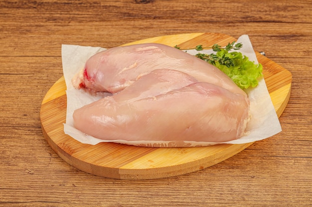 Raw chicken breast over board