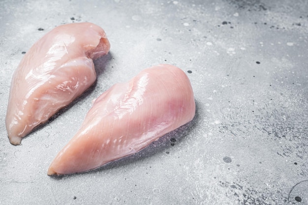 Raw chicken breast fillet on butcher table. Gray background. Top view. Copy space.