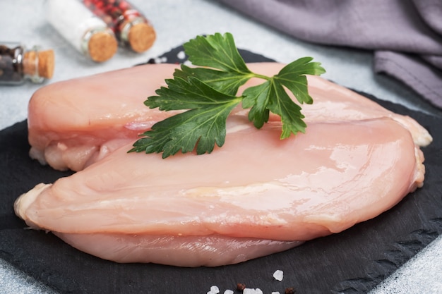 Filetto di petto di pollo crudo, carne di pollo cruda su supporto nero, grigio.