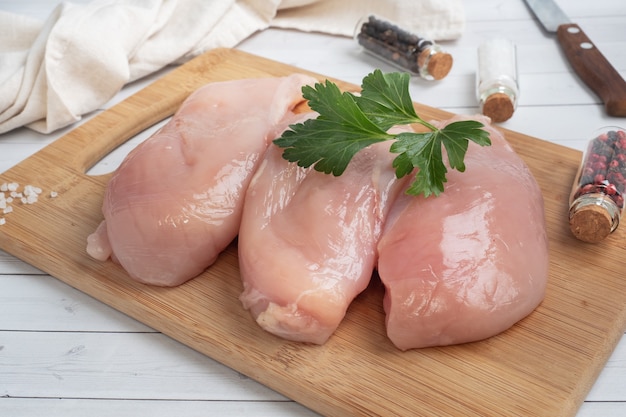 Raw chicken breast fillet, raw chicken meat on a cutting Board. White background,