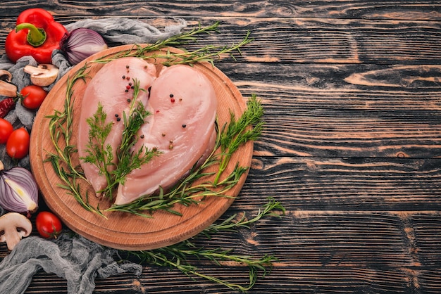 新鮮な野菜とローズマリーとスパイスと黒の木製の背景に生の鶏胸肉の切り身上面図テキストの空きスペース