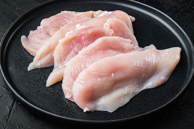 Raw chicken breast fillets, on black table