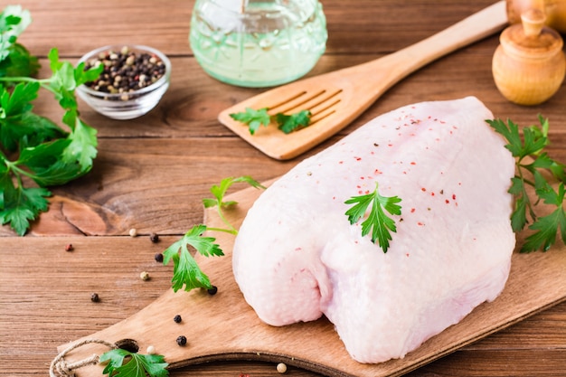 Raw chicken breast on a frame in spices and herbs on a cutting board on a wooden table