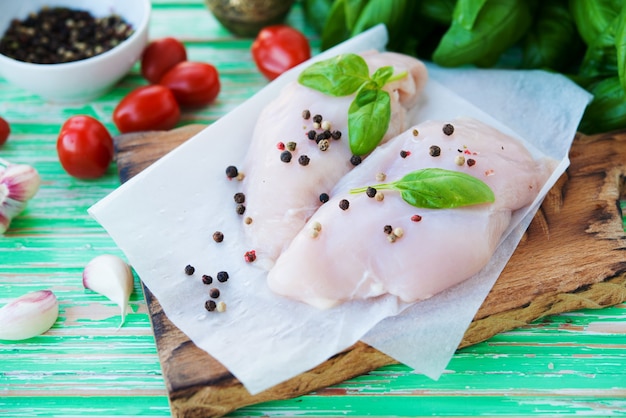 Raw chicken breast marinated for baking on a wooden board, selective focus