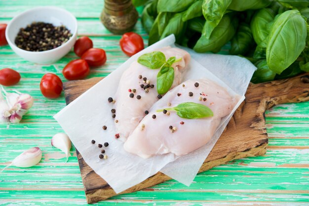 Raw chicken breast marinated for baking on a wooden board, selective focus