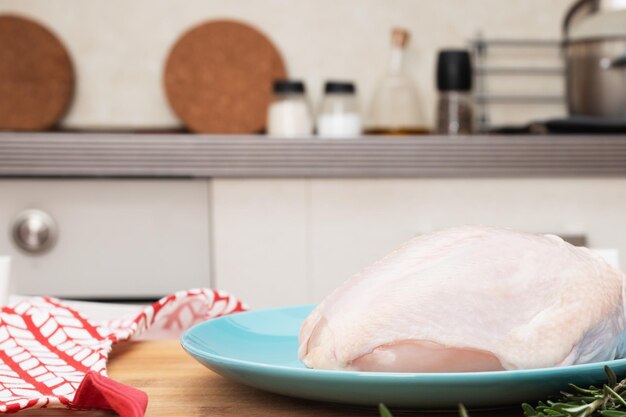 Raw chicken breast on a table on a blue plate in the kitchen before cooking