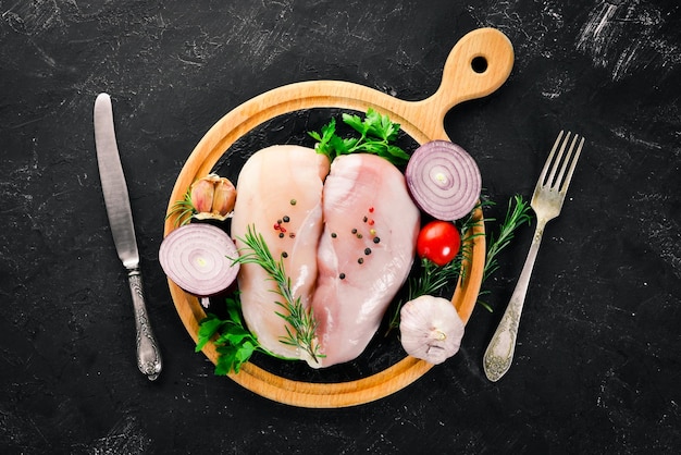 Raw chicken breast with spices and herbs Barbecue On a black stone background Top view Free copy space